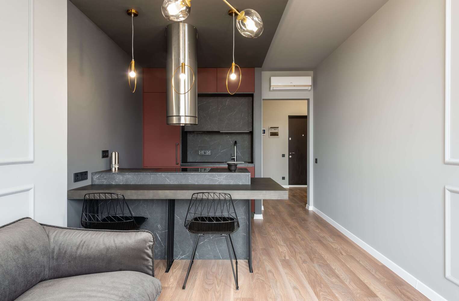 Gray kitchen interior within a luxury apartment. Gray couch on the side after having apartment-kitchen-countertop installationl